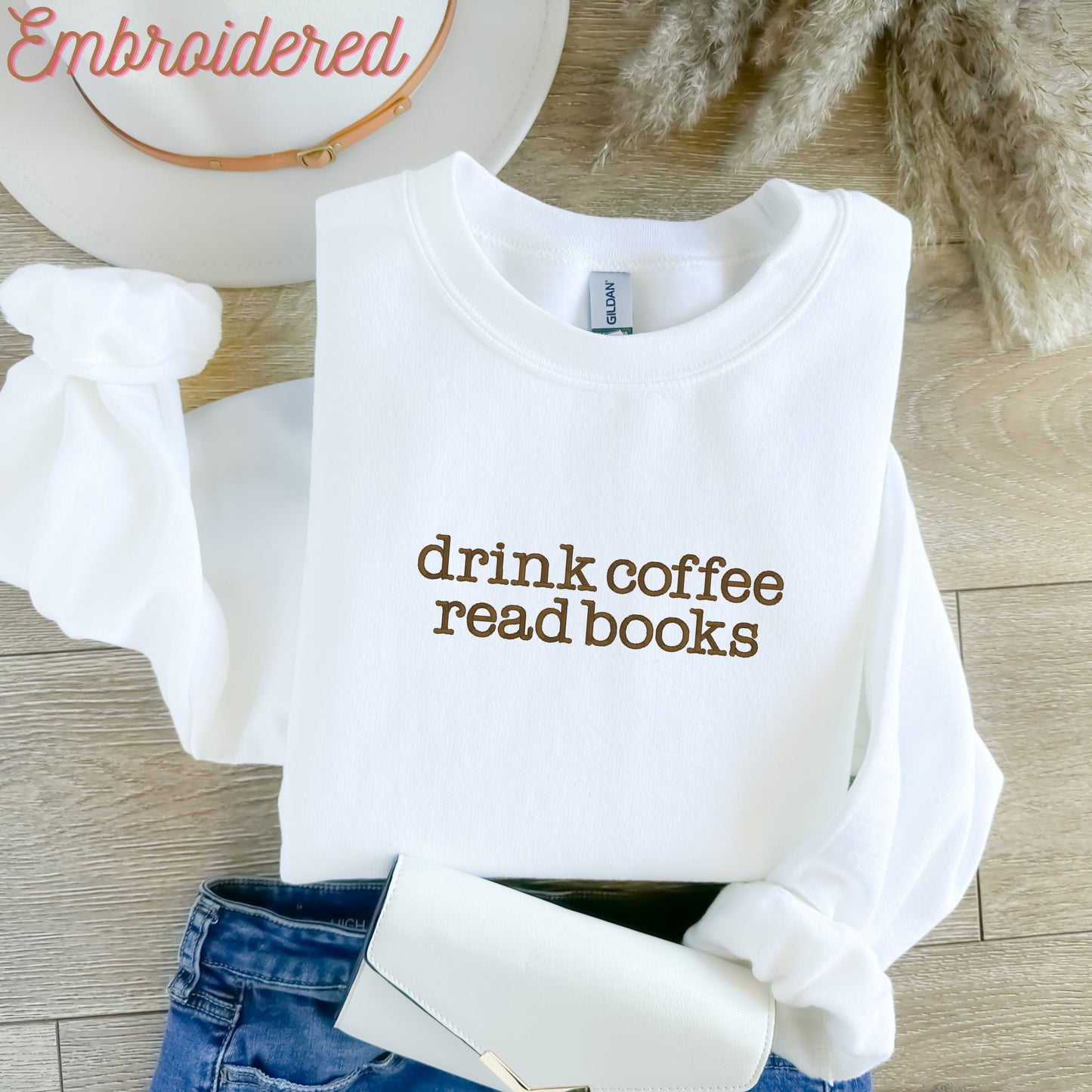 White crewneck cozy fleece lined sweatshirt with "drink coffee read books" embroidered on the front. (Can customize thread color)