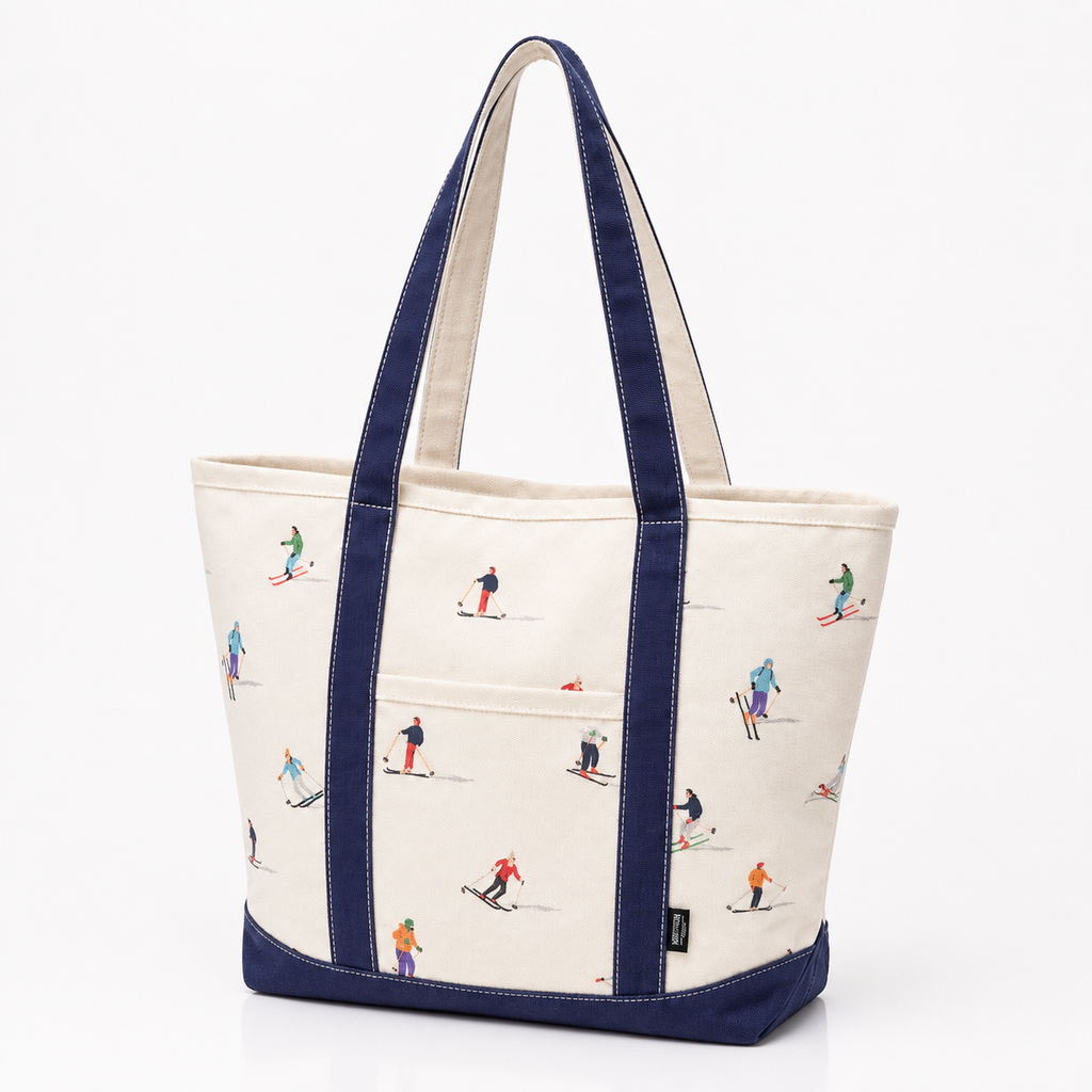 An off-white canvas tote bag with navy blue handles and bottom trim, decorated with a repeating pattern of small skiers in various colorful outfits.
