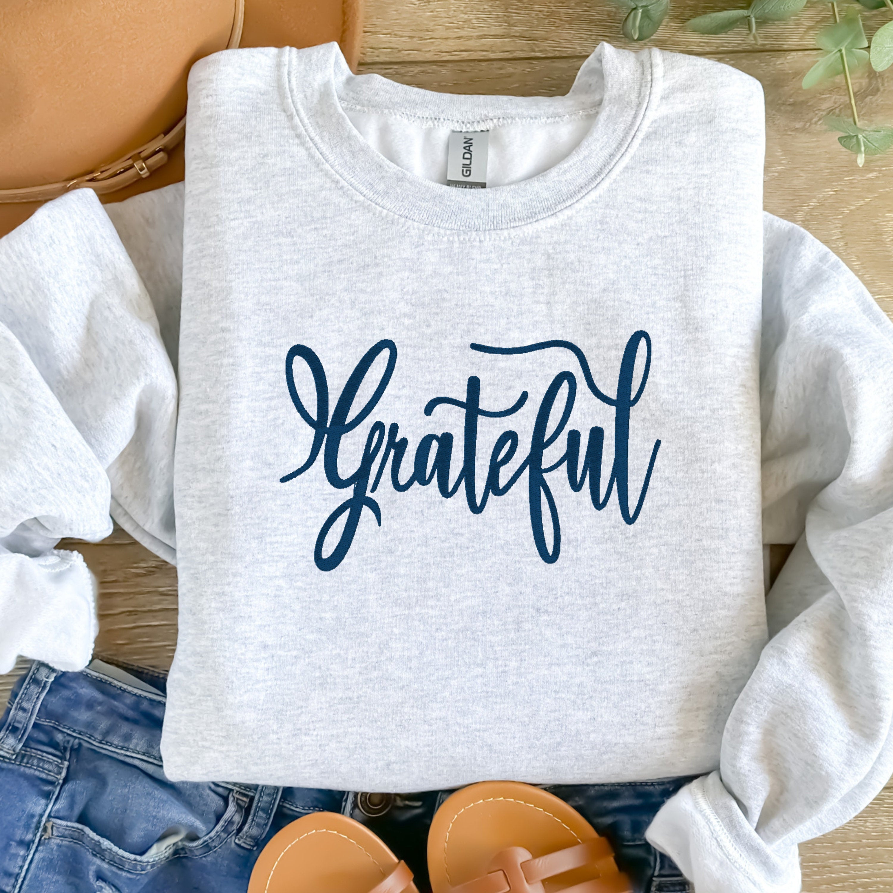Ash gray cozy crewneck sweatshirt with the word Grateful embroidered onto the front chest area. Personalize with different color thread.