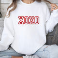 A white crewneck sweatshirt with XOXO embroidered on the front.