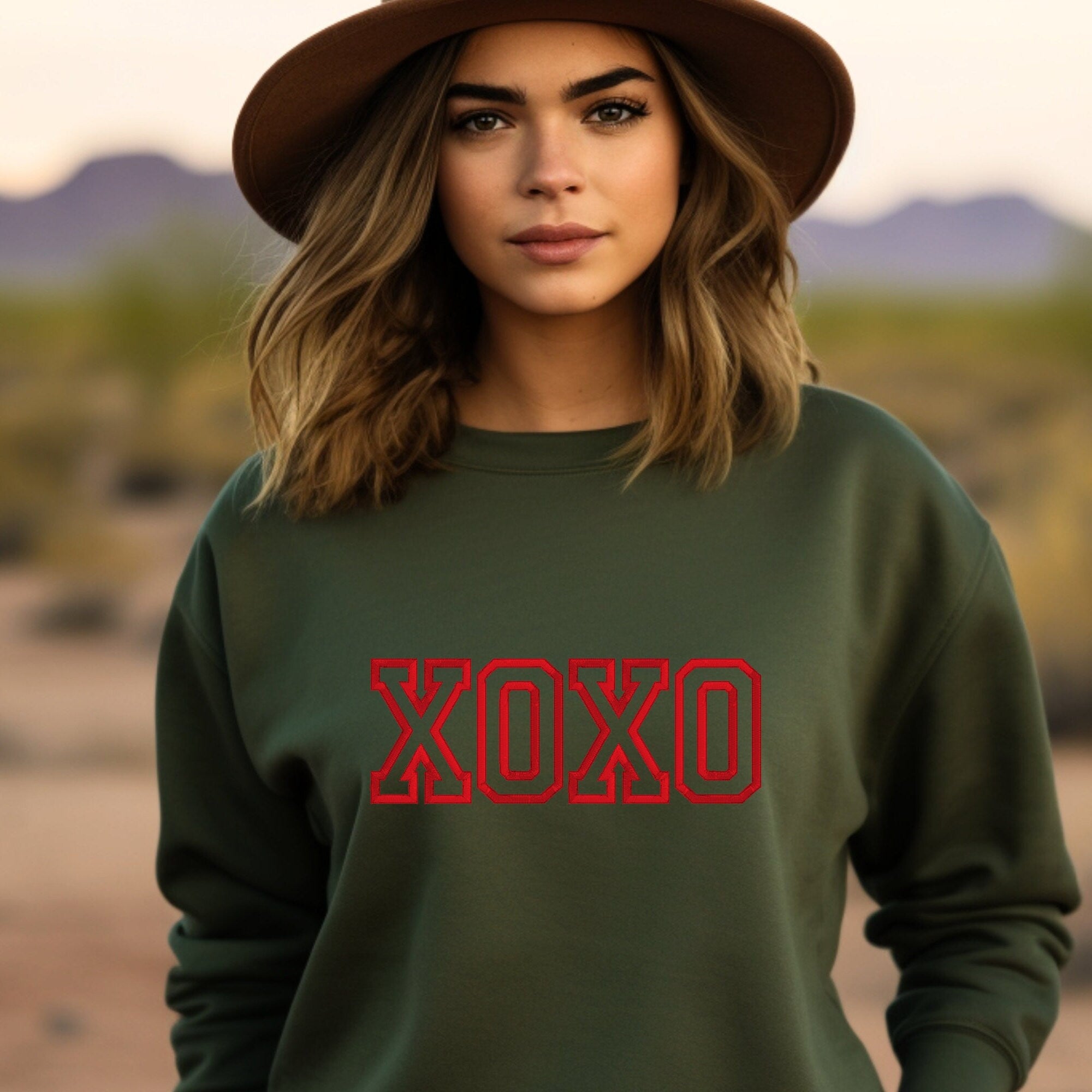 Military green crewneck sweatshirt with red embroidered XOXO on the front.
