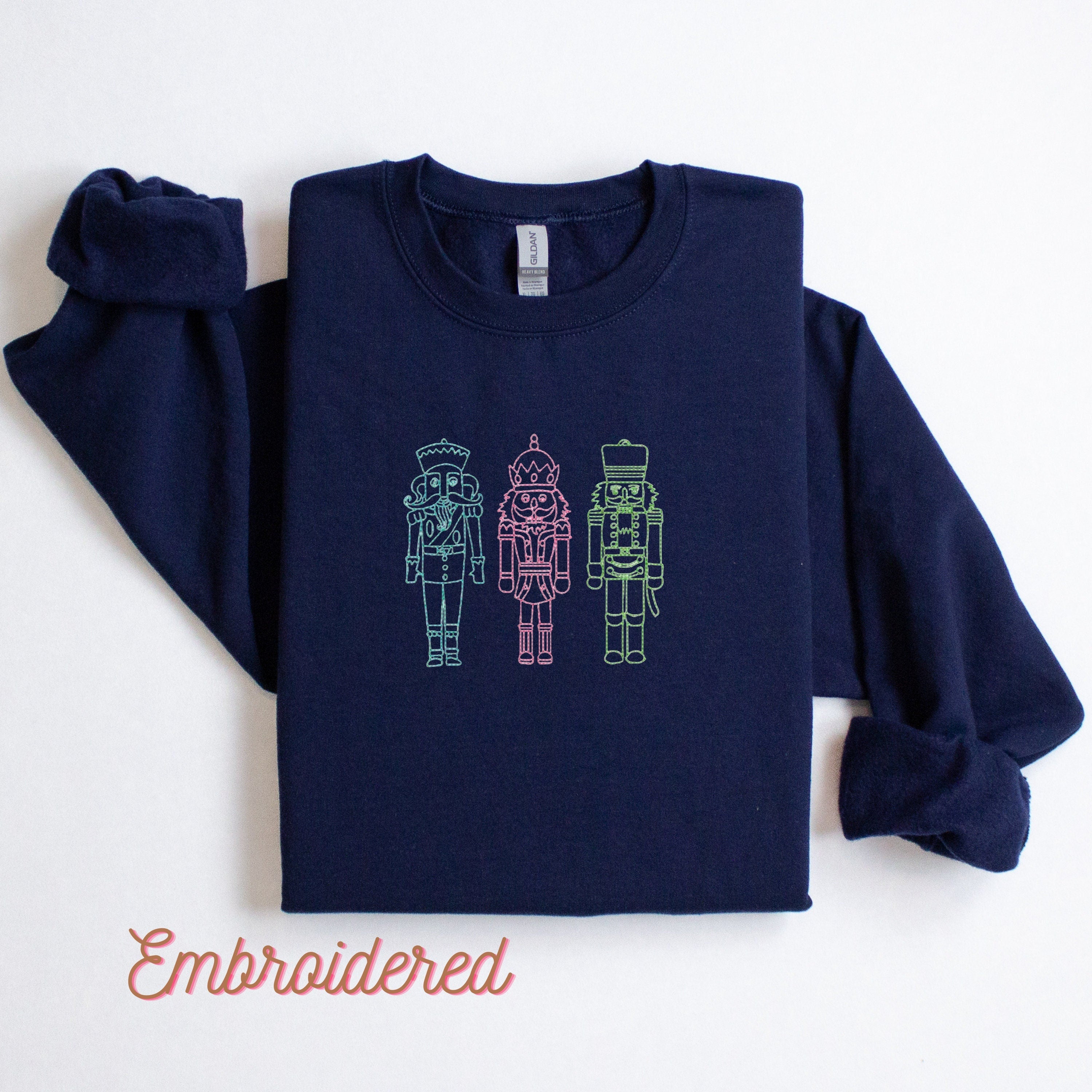 Navy blue fleece lined crewneck, embroidered with 3 nutcrackers on the front. (Blue,Pink & Green thread)
