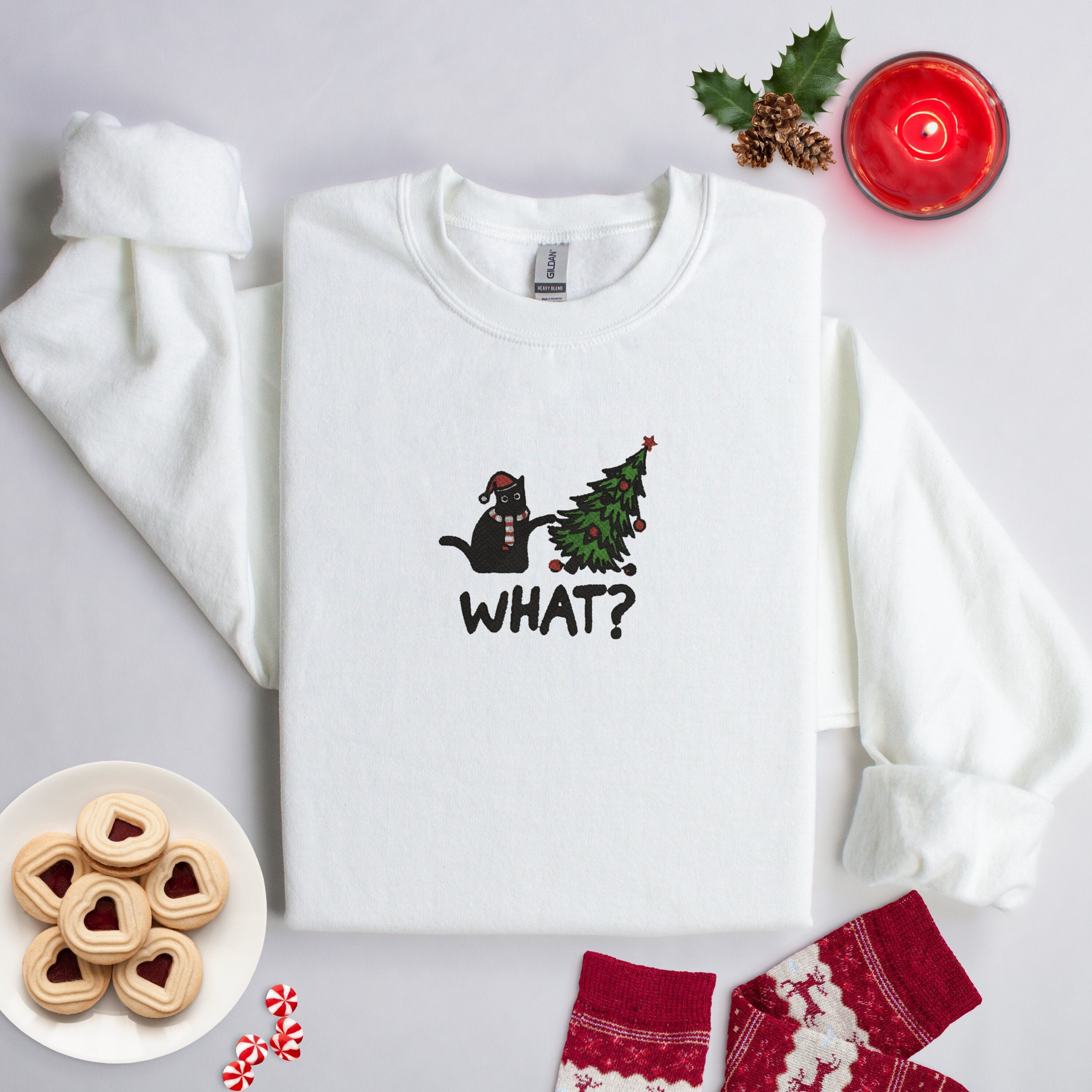 White Crewneck FLeece Lined Christmas Sweatshirt with a &quot;Cat knocking over a tree - What?&quot; embroidered onto the front.