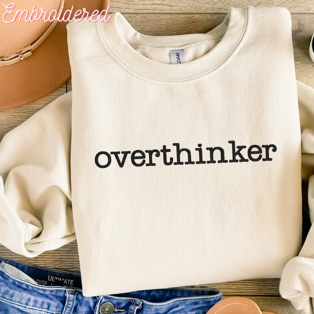 Overthinker embroidered onto a stone colored fleece lined crewneck sweater