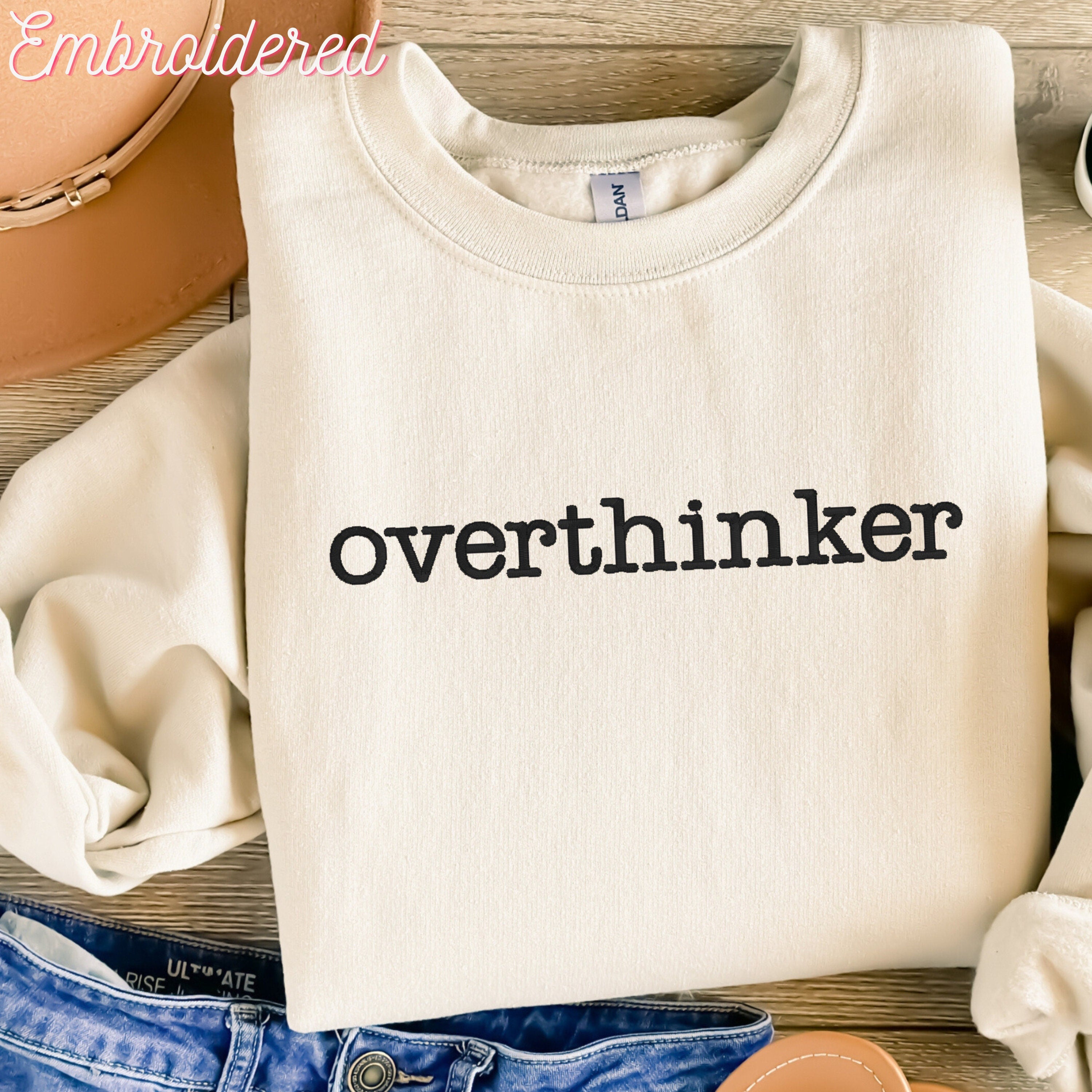 Overthinker embroidered onto a stone colored fleece lined crewneck sweater