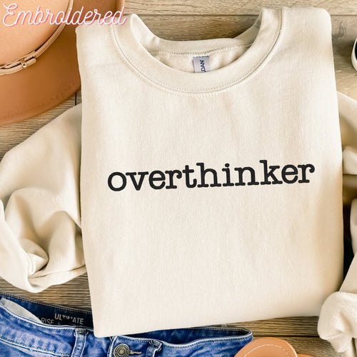 Overthinker embroidered onto a stone colored fleece lined crewneck sweater