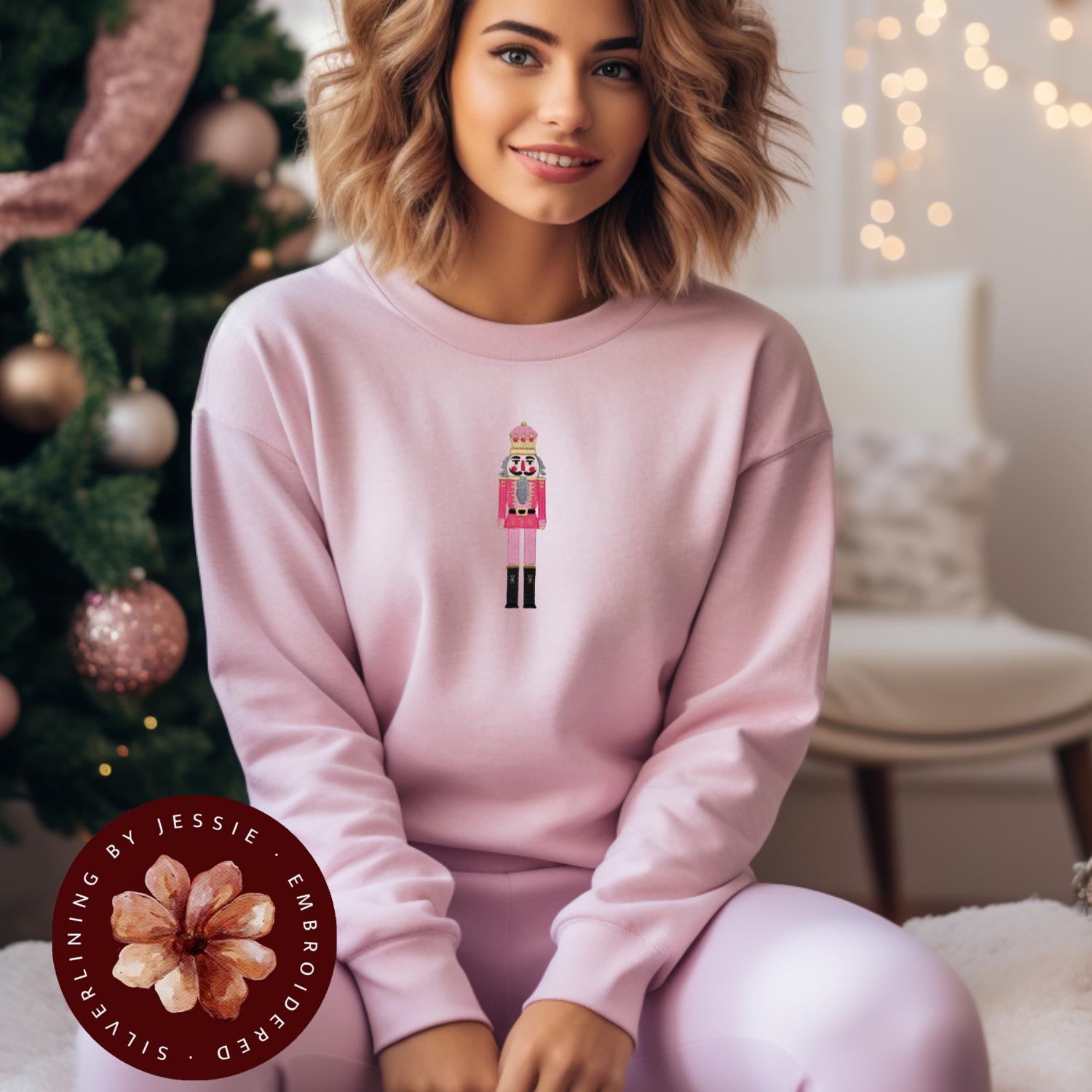 Pink crewneck fleece lined sweatshirt with a pink nutcracker embroidered onto the front.