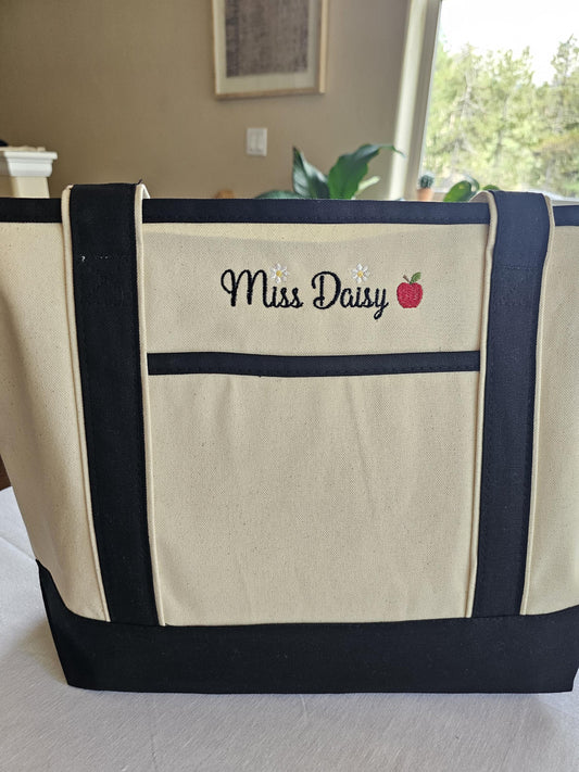 Beige Canvas Tote embroidered with Teachers name with a red apple next to it.