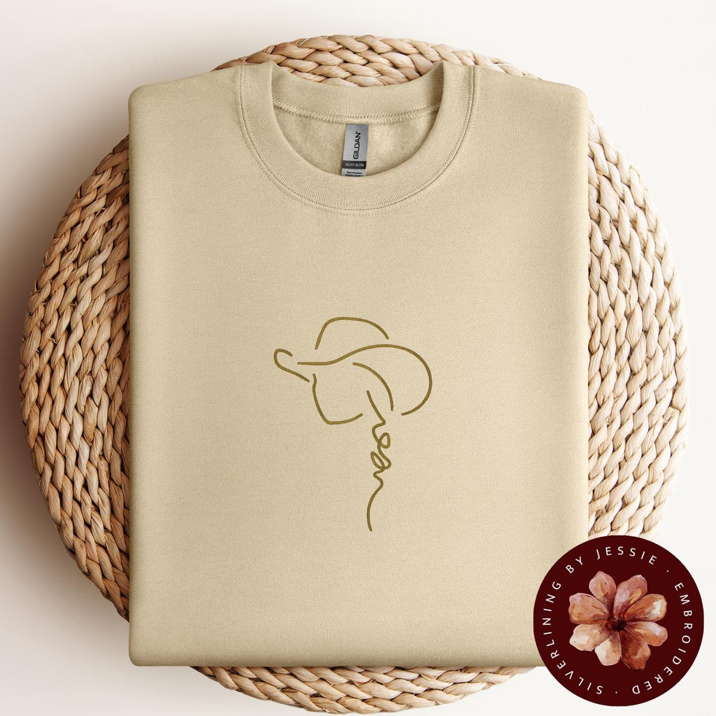 Tan Cowgirl with Hat outline stitched onto a sand cozy crewneck fleece lined sweatshirt